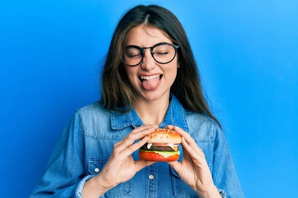 Mladý Kavkazský Žena Jíst Chutný Klasický Burger Vyčnívat Jazyk Šťastný — Stock fotografie