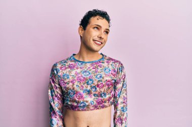 Makyaj yapan yakışıklı bir adam. Moda kıyafetleri giyiyor. Yüzünde gülümseme, doğal bir ifade var. Kendinden emin gülen. 