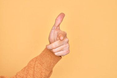 İzole edilmiş sarı arka plan üzerinde parmaklarını gösteren beyaz bir genç adamın eli kamerayı işaret ediyor ve yönü gösteriyor.