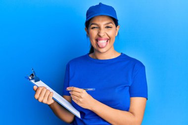 Güzel esmer kadın kurye üniforması giyiyor. Elinde pano var. Dilini komik bir ifadeyle dışarı çıkarıyor.. 