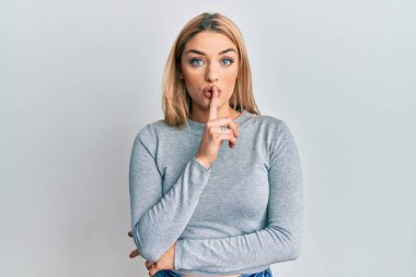 Gündelik giysiler giyen genç beyaz kadın sessiz olmak istiyor dudakları parmaklarla. sessizlik ve gizli konsept. 