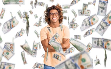 Gündelik kıyafetler ve gözlük takan genç İspanyol adam kameraya bakarken kollarını kavuşturup gülümsüyor. pozitif kişi.