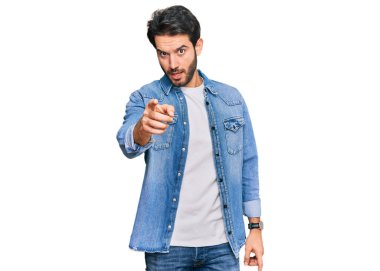 Gündelik kıyafetler giyen genç İspanyol adam kameraya kızgın ve sinirli bir şekilde seni işaret ediyor. 