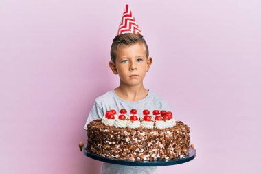 Adorable caucasian kid celebrating birthday with cake relaxed with serious expression on face. simple and natural looking at the camera.  clipart