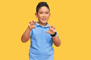 Küçük İspanyol çocuk gündelik kıyafetler giyip gülümsüyor. Pençe hareketlerini kedi gibi yapıyor. Agresif ve seksi bir ifade. 