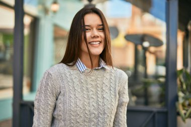 Genç İspanyol kız gülümseyerek şehirde mutlu mesut dikiliyor..