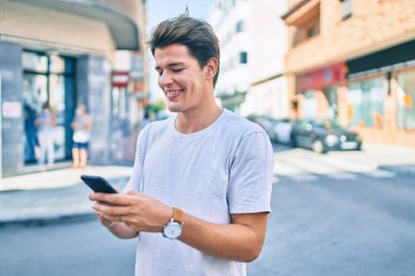 Beyaz adam şehirde akıllı telefon kullanarak mutlu bir şekilde gülümsüyor..