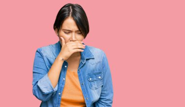 Kısa saçlı, güzel İspanyol bir kadın sıradan bir kot ceket giyiyor kendini iyi hissetmiyor ve soğuk algınlığı veya bronşitin belirtisi olarak öksürüyor. sağlık hizmeti kavramı. 