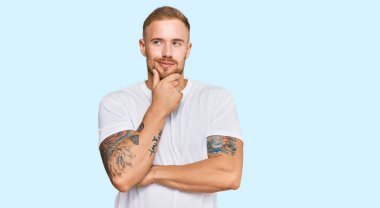 Elleri çenesinde gündelik kıyafetler giyen genç İrlandalı sorgulamayı, düşünceli ifadeyi düşünüyor. Düşünceli bir yüzle gülümsüyor. şüphe kavramı. 