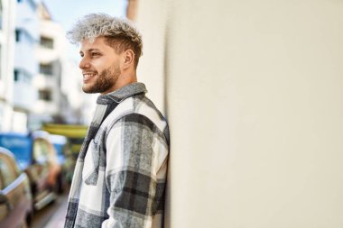 Genç İspanyol adam gülümseyerek şehirde mutlu mesut dikiliyor..