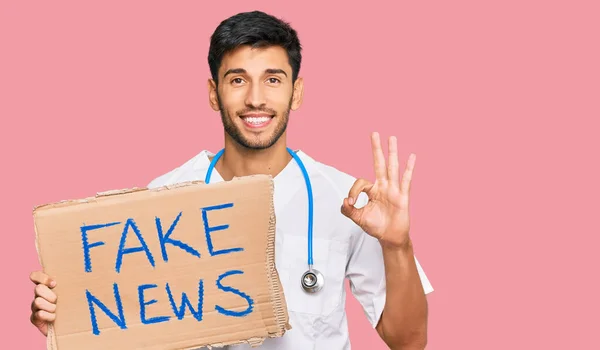 Joven Hombre Guapo Vistiendo Uniforme Médico Sosteniendo Pancarta Noticias Falsas — Foto de Stock