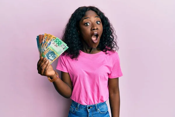 Hermosa Mujer Joven Africana Sosteniendo Dólares Australianos Asustada Sorprendida Con —  Fotos de Stock