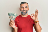 Pohledný muž středního věku drží 20 dolarů bankovky dělá v pořádku znamení s prsty, usmívá přátelské gesto vynikající symbol 