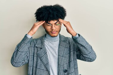 Afro saçlı, elleri kafasında günlük kıyafet gözlüğü takan, başı ağrıdığı için başı ağrıyan Afrikalı genç bir Amerikalı. migren ağrısı. 