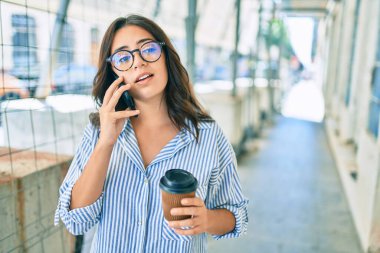 Ciddi bir suratı olan genç İspanyol iş kadını şehirdeki akıllı telefondan konuşuyor..