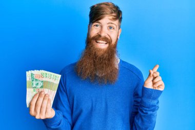 Genç İrlandalı kızıl saçlı adam Hong Kong 'u tutuyor. 50 dolarlık banknotlar gülümsüyor. 