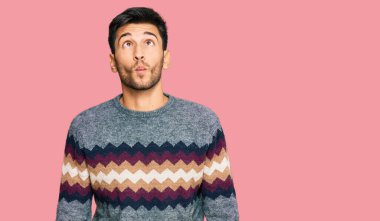 Kış süveteri giyen genç yakışıklı adam dudaklarıyla balık suratı yapıyor, çılgınca ve komik bir jest. Komik ifade. 