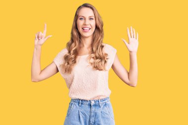 Sarışın, güzel, beyaz bir kadın. Günlük kıyafetler giyiyor. Yedi numaralı parmaklarıyla işaret ediyor.. 