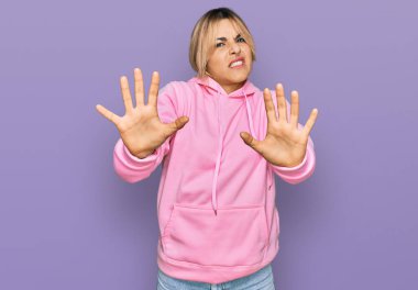 Kafkasyalı genç bir kadın günlük kazak giyiyor. Korkudan dehşete düşmüş ve korkmuş. El kol hareketi yapmayı kes, şok içinde bağırmayı kes. panik konsepti. 