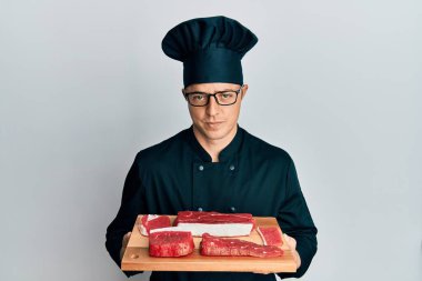 Yakışıklı, şef üniforması giyen genç bir adam. Elinde çiğ et, şüpheci ve gergin bir halde duruyor. Problemden dolayı suratını asıyor. negatif kişi. 