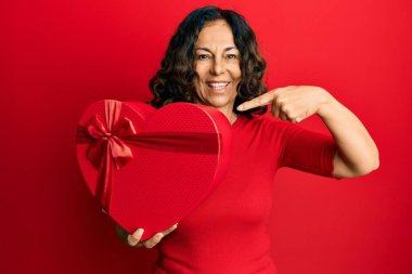 Orta yaşlı İspanyol kadın sevgililer günü hediyesini tutarken mutlu bir şekilde elini ve parmağını gösterdi. 