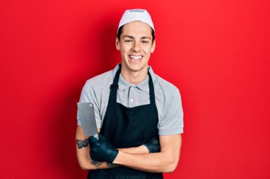 Profesyonel üniforma giyen İspanyol dövmeli genç adam ve elinde kızgın yüzlü dövme makinesi tutan eldivenler, olumsuz işaretler baş parmakları aşağıda, reddedilme konsepti. 