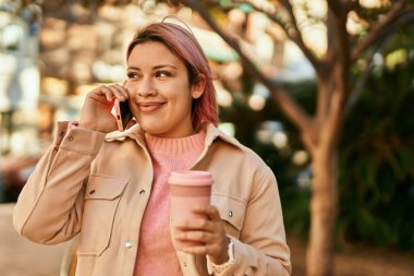 Genç İspanyol kız akıllı telefondan konuşuyor ve şehirde kahve içiyor..