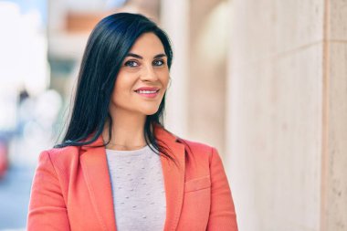 Genç ve güzel bir iş kadını gülümseyerek şehirde mutlu mesut duruyor..