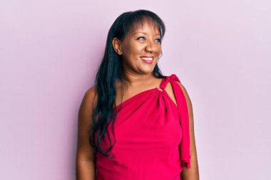 Orta yaşlı Afro-Amerikalı kadın günlük giysiler giyiyor, rahat profil pozu veriyor doğal bir yüzü ve kendine güvenen bir gülüşü var.. 