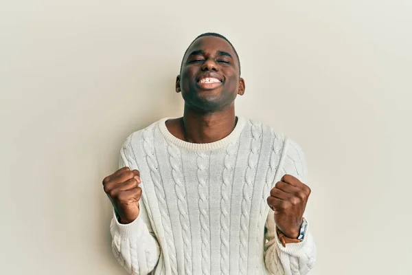 若いアフリカ系アメリカ人の男性が腕を上げて成功に興奮したカジュアルな服を着て 目を閉じて勝利を笑顔を祝う 勝者のコンセプト — ストック写真