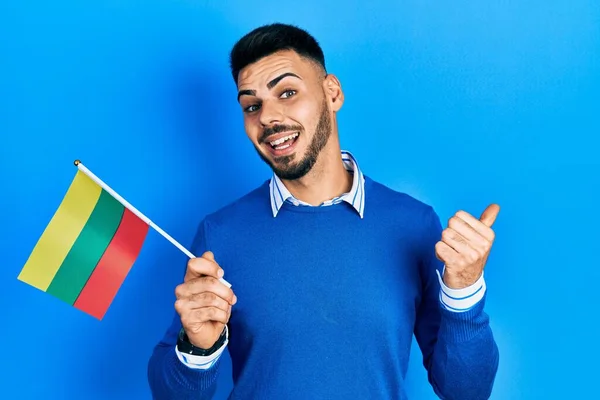 年轻的男子 留着胡子 拿着立陶宛国旗 大拇指指向旁边 笑着张开了嘴 — 图库照片