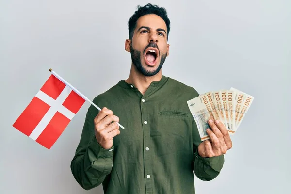 Młody Hiszpan Trzymający Flagę Denmarkową Banknoty Koronowe Wściekły Wściekły Krzyczący — Zdjęcie stockowe