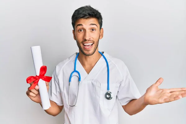 Jovem Homem Bonito Vestindo Uniforme Médico Segurando Grau Médico Celebrando — Fotografia de Stock