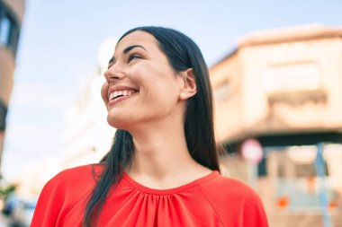 Genç Latin kız gülümseyerek şehirde mutlu mesut yürüyor..