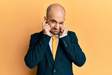 Genç İspanyol bir adam iş elbisesi ve kravat takıyor. Yüksek sesli müzik sesi için kulaklarını parmaklarıyla kapatıyor. sağır kavramı. 