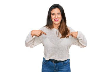 Güzel İspanyol kadın gündelik süveter giyiyor. Kendine güveniyor gibi görünüyor. Yüzünde gülücükler, parmakları gururlu ve mutlu birini gösteriyor.. 