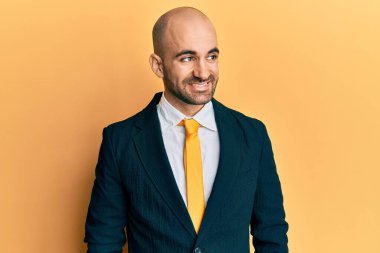 Genç İspanyol takım elbiseli ve kravatlı bir adam yüzünde gülümsemeyle yan yana bakıyor, doğal bir ifade. Kendinden emin gülen. 