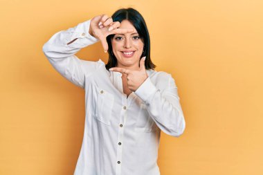 Gündelik kıyafetler giyen, gülümseyen, elleri ve parmakları gülen yüzlü genç İspanyol kadın. yaratıcılık ve fotoğrafçılık kavramı. 