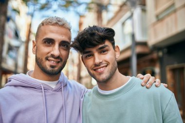 Mutlu bir şekilde gülümseyen ve şehirde sarılan genç eşcinsel çift..