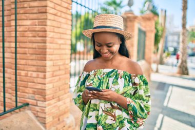 Genç Afro-Amerikan turist kadın tatilde gülümsüyor. Şehirde akıllı telefon kullanıyor..
