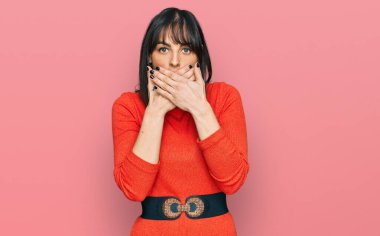 Gündelik kıyafetler giyen genç İspanyol kadın yanlışlıkla elleri ile ağzını kapatırken şok oldu. gizli kavram. 