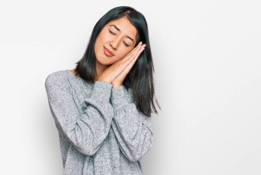 Güzel Asyalı genç kadın gündelik giysiler giyip uyuyordu. Yorgun düşler görüyordu. Elleriyle poz verirken gözleri kapalıydı.. 