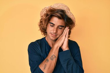 Yaz şapkası takan genç İspanyol adam yorgun uyur, hayal kurar ve elleriyle poz verir, gözleri kapalı gülümserdi.. 