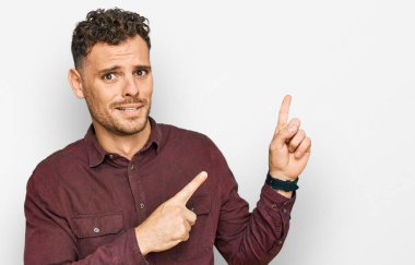 Gündelik kıyafetler giyen genç İspanyol bir adam iki eliyle endişeli ve endişeli bir ifadeye işaret ediyor. 