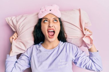 Ortadoğulu güzel bir kadın uyku maskesi takmış ve pijama giymiş kızgın ve kızgın bir şekilde uyuyor. Öfkeli ve öfkeliydi. Öfkeyle bağırıyordu.. 