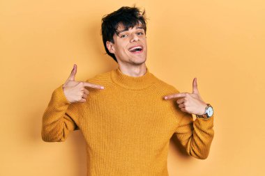 Yakışıklı hippi genç adam gündelik sarı süveter giyiyor. Kendine güvenen, gülümseyen, kendini gururlu ve mutlu gösteren.. 