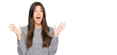 Kışlık süveter giyen genç esmer kadın çılgın ve başarıyı kollarını kaldırıp heyecanla haykırarak kutluyor. Kazanan konsept 