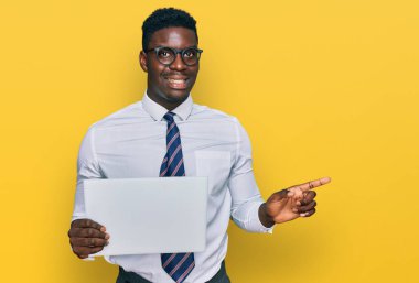 Yakışıklı iş adamı boş afiş tutuyor, gülümsüyor, mutlu bir şekilde eli ve parmağı yana bakıyor. 