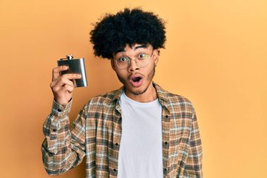 Afro saçlı, viski şişesinden alkol içen, ağzı açık, ağzı açık, şaşırmış ve şaşırmış genç Afrikalı Amerikalı bir adam. 