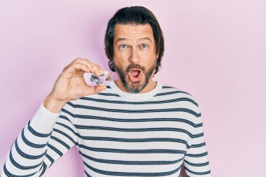 Orta yaşlı beyaz bir adam elinde pırlanta bir taş tutuyordu. Şaşırtmak için ağzı açık ve korkmuştu. İnanmayan yüz. 